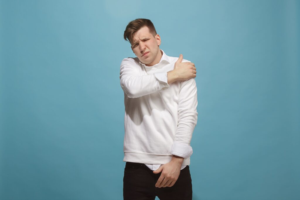 Person in white hoodie is suffering with left arm pain against blue background.