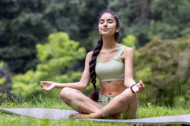 A young Indian woman in a green tracksuit performs yoga
