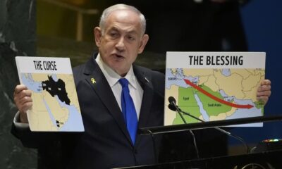 Prime Minister of Israel Benjamin Netanyahu hold signs as he addresses the 79th session of the United Nations General Assembly on Friday.