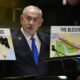 Prime Minister of Israel Benjamin Netanyahu hold signs as he addresses the 79th session of the United Nations General Assembly on Friday.